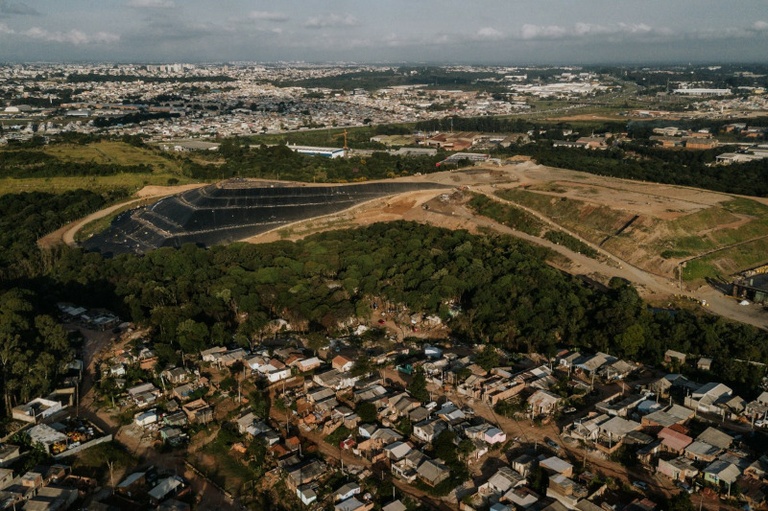 A Ocupação Tirandentes 2, na imagem acima, são as casas entre as árvores que separam o aterro da Tiradentes 1. (Foto: Rodrigo Fonseca/CMC)